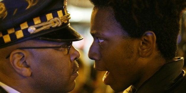 Lamon Reccord, right, stares and yells at a Chicago police officer "Shoot me 16 times" as he and others march through Chicago's Loop Wednesday, Nov. 25, 2015, one day after murder charges were brought against police officer Jason Van Dyke in the killing of 17-year-old Laquan McDonald. (AP Photo/Charles Rex Arbogast)