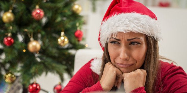 Beautiful young woman wearing Santa's hat is feeling sad and sitting on the home at Christmas Time.