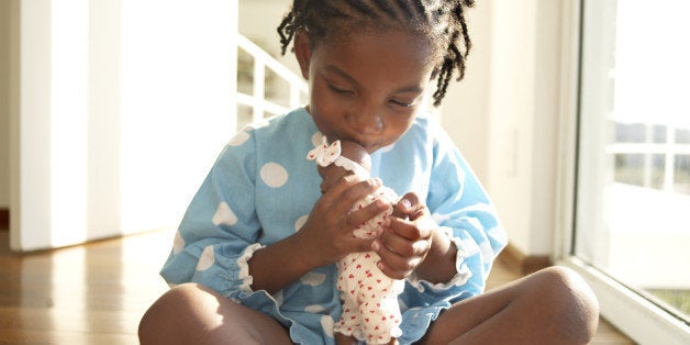 Girl (3-5) kissing doll on floor, close-up