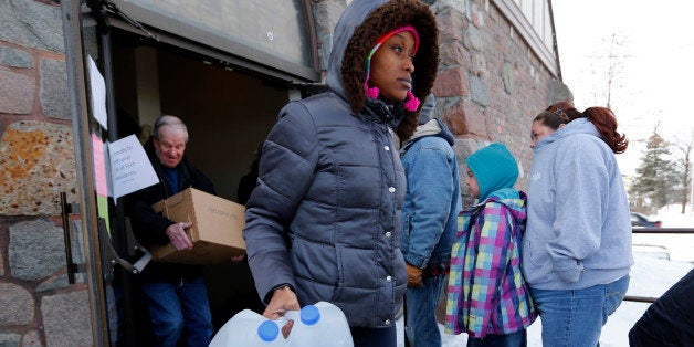 In this Tuesday, Feb. 3, 2015 photo, Genetha Campbell carries free water being distributed at the Lincoln Park United Methodist Church in Flint, Mich, Since the financially struggling city broke away from the Detroit water system last year, residents have been unhappy with the smell, taste and appearance of water from the cityâs river as they await the completion of a pipe to Lake Huron. They also have raised health concerns, reporting rashes, hair loss and other problems. A General Motors plant stopped using the water, saying it was rusting its parts. (AP Photo/Paul Sancya)