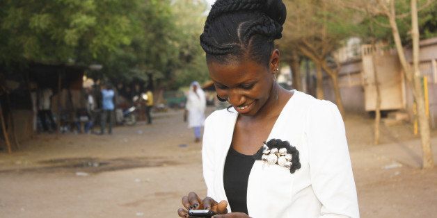 A smiling young woman writing a texto on her mobile phone.