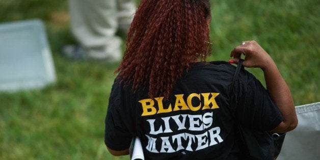 A woman wears a shirt with 'Black Lives Matter' during a memorial service for slain 18 year-old Michael Brown Jr. on August 9, 2015 at the Canfield Apartments in Ferguson, Missouri. Several hundred demonstrators stood in silence Sunday at the spot where an unarmed black teen was shot and killed by a white police officer one year ago, throwing America's troubled race relations into harsh relief. Two white doves were released over the crowd that gathered to mark the anniversary of 18-year-old Michael Brown's death in a fateful encounter August 9, 2014 with white police officer Darren Wilson. The crowd, about 300 strong, observed four and a half minutes of silence, one minute for each of the four and a half hours that Brown's body lay face down in the street before being taken away. AFP PHOTO / MICHAEL B. THOMAS (Photo credit should read Michael B. Thomas/AFP/Getty Images)