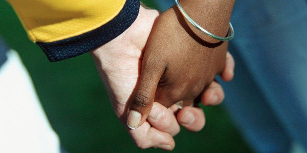 Young man's and woman's clasped hands, close up.