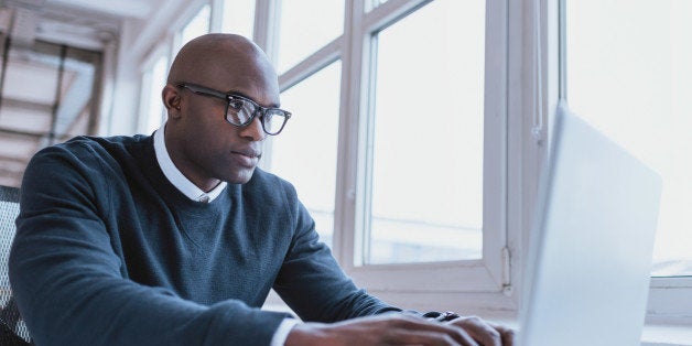 Image of african american businessman working on his laptop. Handsome young man at his desk.