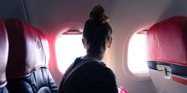 Woman Looking Through Window While Traveling In Airplane