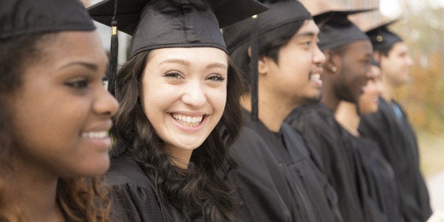 Six multi-ethnic friend graduates excitedly wait for their name to be called during graduation ceremony. Mixed-race girl look