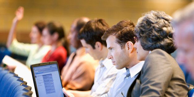 Business people sitting in lecture hall with laptop