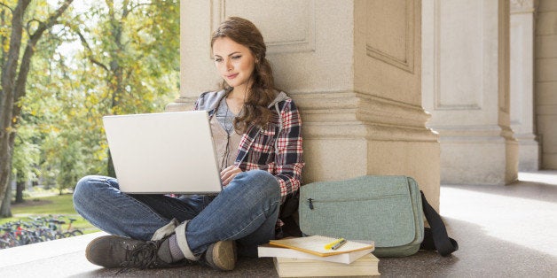 College student studying with laptop and earbuds