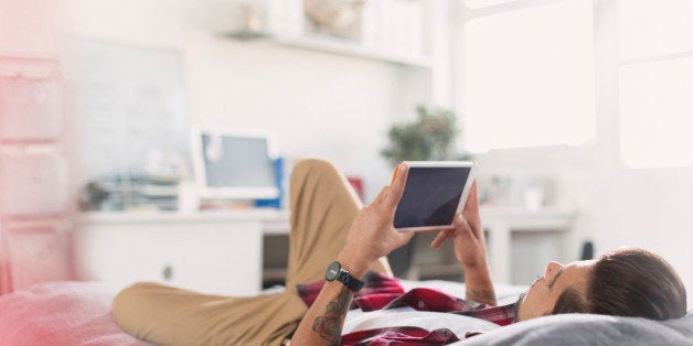 Young man using digital tablet on bed