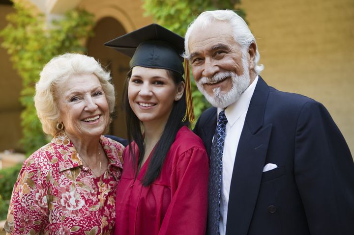 Portrait of a young female graduate with grandparents smiling