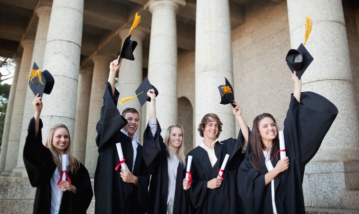 smiling graduates holding up...