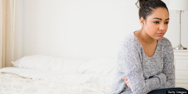 Hispanic woman thinking on bed