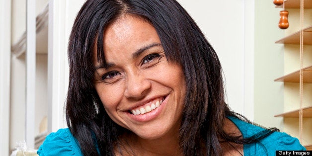 A pretty young Latino girl relaxes at home and enjoys passing the time with a good book.