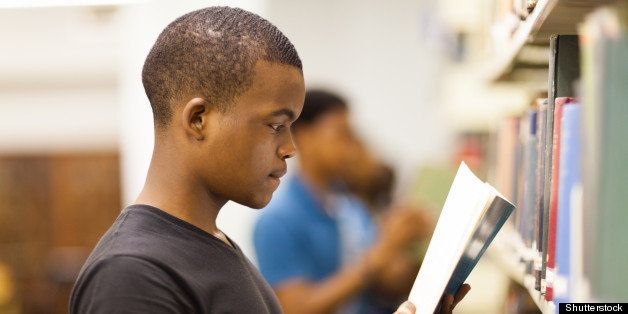 male african college student reading in library