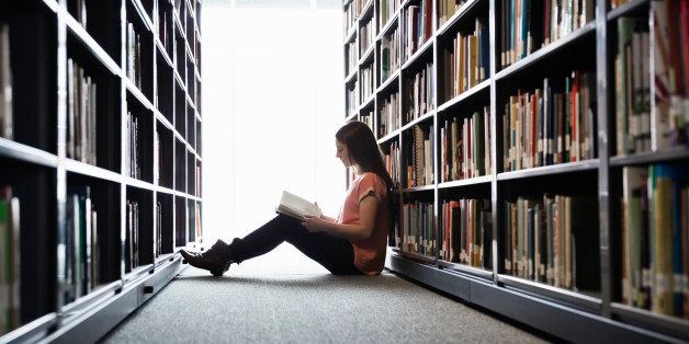 Female student sitting on library floor at college campus