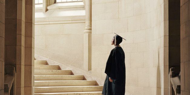 Women wearing graduation cap and gown, ascending staircase, rear view