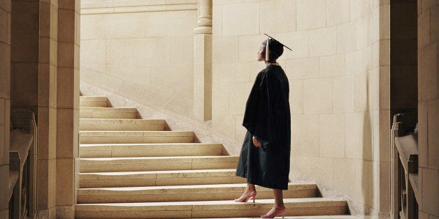 Women wearing graduation cap and gown, ascending staircase, rear view