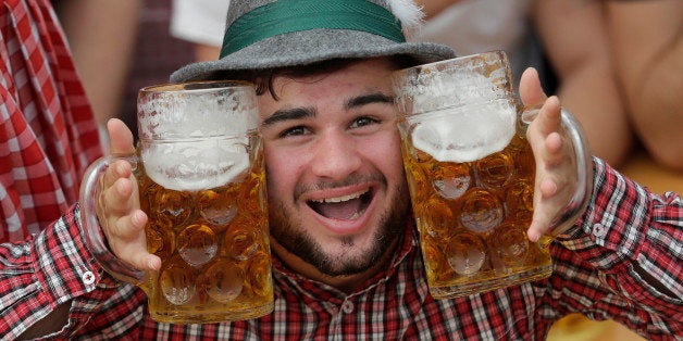 A young man poses with beer mugs at the second weekend in the 'Hofbraeuhaus beer tent' at the famous beer festival Oktoberfest in Munich, southern Germany, Sunday, Sept. 28, 2014. The world's largest beer festival will be held from Sept. 22 to Oct. 5, 2014. (AP Photo/Matthias Schrader)