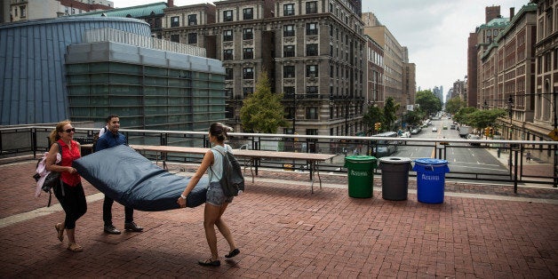 NEW YORK, NY - SEPTEMBER 05: Emma Sulkowicz (R), a senior visual arts student at Columbia University, carries a mattress, with the help of two strangers who met her moments before, in protest of the university's lack of action after she reported being raped during her sophomore year on September 5, 2014 in New York City. Sulkowicz has said she is committed to carrying the mattress everywhere she goes until the university expels the rapist or he leaves. The protest is also doubling as her senior thesis project. (Photo by Andrew Burton/Getty Images)