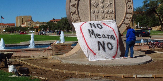 Texas Tech freshman Regan Elder helps drape a bed sheet with the message " No means No," over the university's seal on the Lu