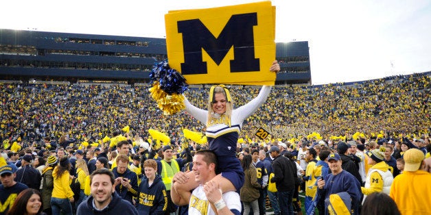 ANN ARBOR, MICHIGAN - NOVEMBER 26, 2011: A cheerleader from the University of Michigan is carried around on the shoulders of another cheerleader while fans celebrate on the field after a game between the Ohio State Buckeyes and Michigan Wolverines at Michigan Stadium in Ann Arbor, Michigan. The Wolverines won 40-34. (Photo by David Dermer/ Diamond Images/ Getty Images)