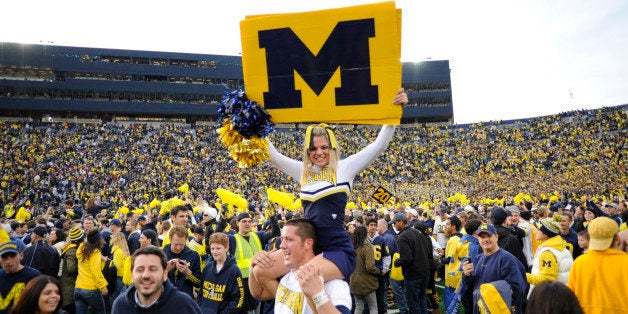 ANN ARBOR, MICHIGAN - NOVEMBER 26, 2011: A cheerleader from the University of Michigan is carried around on the shoulders of another cheerleader while fans celebrate on the field after a game between the Ohio State Buckeyes and Michigan Wolverines at Michigan Stadium in Ann Arbor, Michigan. The Wolverines won 40-34. (Photo by David Dermer/ Diamond Images/ Getty Images) 