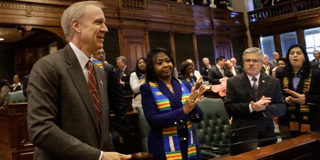 Illinois Gov. Bruce Rauner enters the House to applause to delivers his first budget address to a joint session of the General Assembly in the House chambers Wednesday, Feb. 18, 2015, in Springfield Ill. Illinois Rep. Greg Harris is seen on the far right. (AP Photo/Seth Perlman)