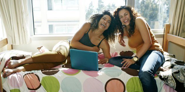 Mixed race college students laughing in dorm