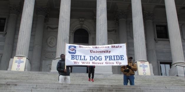 Supports of South Carolina State University hold up a banner at a Statehouse rally against against a proposal to close South
