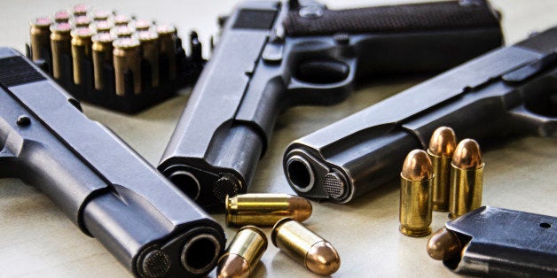 Three pistols laying on table with bullets