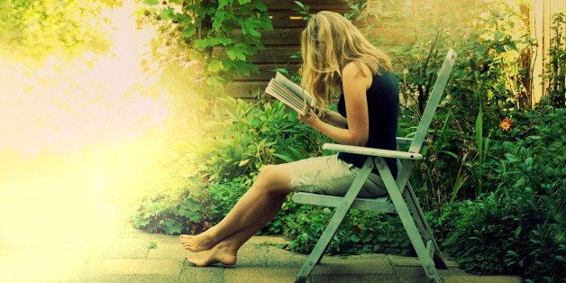 young woman reading outside in beautifully lit green summer garden