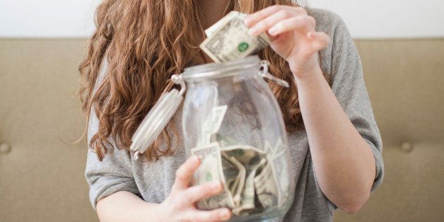 USA, Utah, Salt Lake City, Young woman putting money into her savings jar