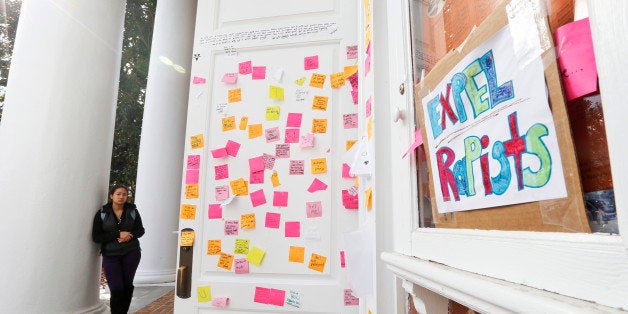 A University of Virginia student looks over postings on the door of Peabody Hall related to the Phi Kappa Psi gang rape allegations at the school in Charlottesville, Va., Monday, Nov. 24, 2014. The university has suspended activities at all campus fraternal organizations amid an investigation into a published report in which a student described being sexually assaulted by seven men in 2012 at the Phi Kappa Psi house. (AP Photo/Steve Helber)