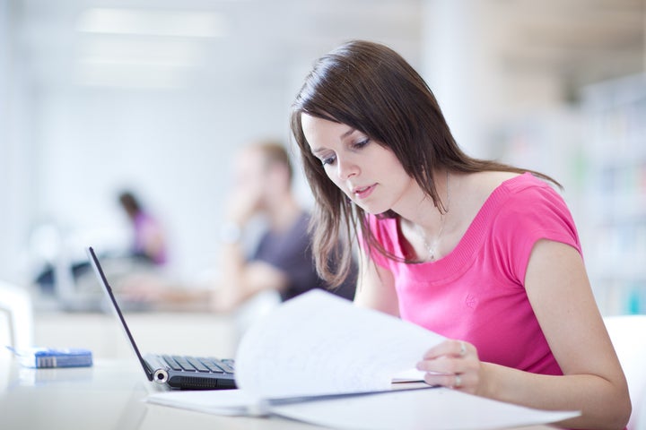 in the library - pretty female student with laptop and books working in a high school library (color toned image)