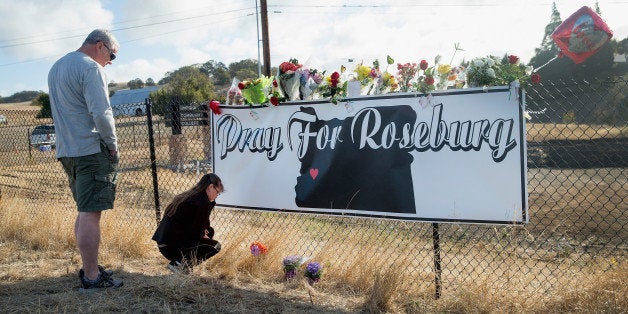 ROSEBURG, OR - OCTOBER 03: Dave (L) and Robin Griffiths leave flowers at a memorial along the road to Umpqua Community Colle