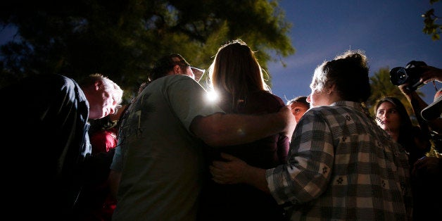 A woman, center, who survived a shooting rampage, talks to members of the media outside a community center after she reunited