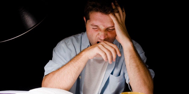 Young Man Yawning tired while Studying at Night