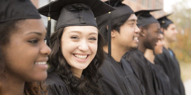 Six multi-ethnic friend graduates excitedly wait for their name to be called during graduation ceremony. Mixed-race girl look