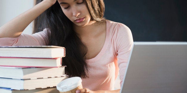 Tired Hispanic teenager holding coffee cup