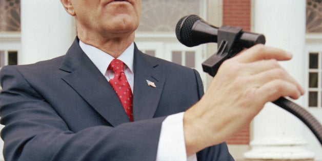 Mature Businessman at lectern outdoors, holding microphone and documents