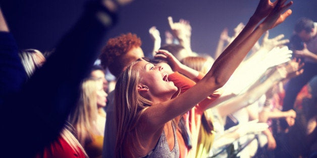 A group of people standing with their arms raised at a concert. This concert was created for the sole purpose of this photo shoot, featuring 300 models and 3 live bands. All people in this shoot are model released.