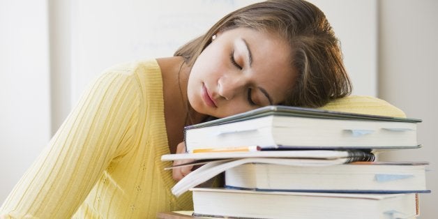 Tired Indian student laying on stack of textbooks