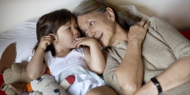 Grandmother and granddaughter (2-3) lying on bed, elevated view