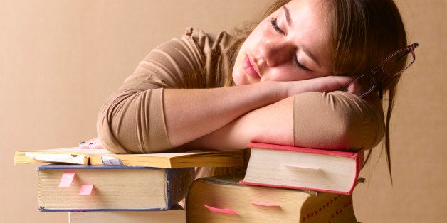 University student falling asleep on text books