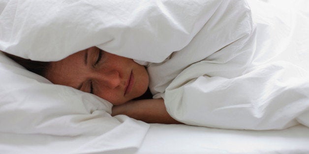 Sick woman sleeping in bed under blanket