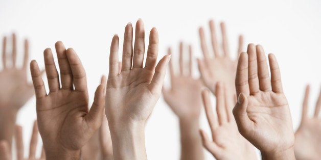 Closeup of multiethnic men and women raising hands against white background