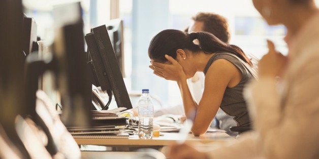 Stressed businesswoman with head in hands at office desk