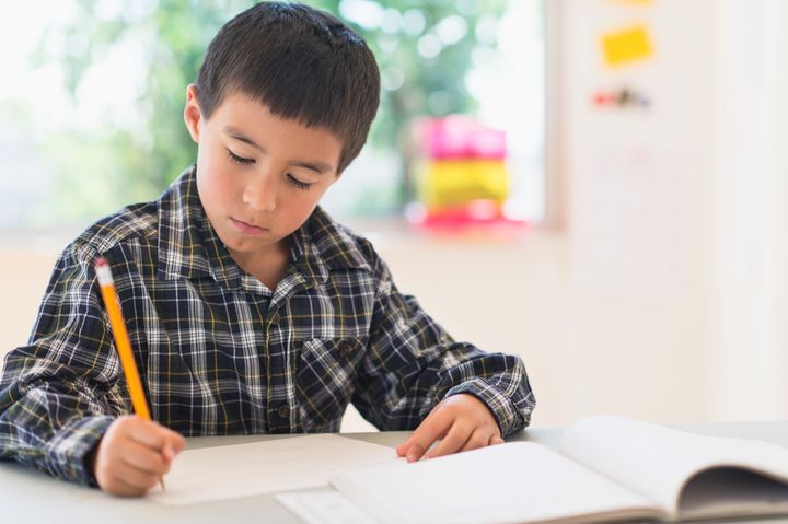 Boy (6-7) writing at school