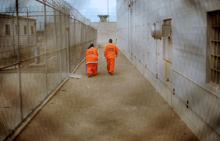 Inmates walk along a fenced area while performing work chores at Deuel Vocational Institution in Tracy, California, U.S., on Thursday, Oct. 11, 2012. The primary purpose of the Deuel Vocational Institution is to serve as a reception center for newly-committed prisoners to the California Department of Corrections and Rehabilitation from northern California county jails as well as house a small number of minimum and low security inmates. Photographer: Noah Berger/Bloomberg via Getty Images