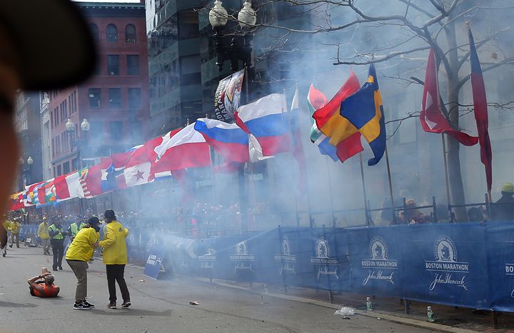 BOSTON - APRIL 15: Officials react as the first explosion goes off on Boylston Street near the finish line of the 117th Boston Marathon on April 15, 2013. (Photo by John Tlumacki/The Boston Globe via Getty Images)